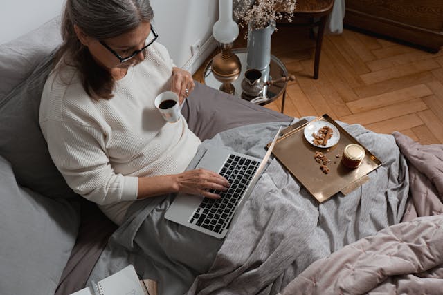 woman working on laptop in her bed